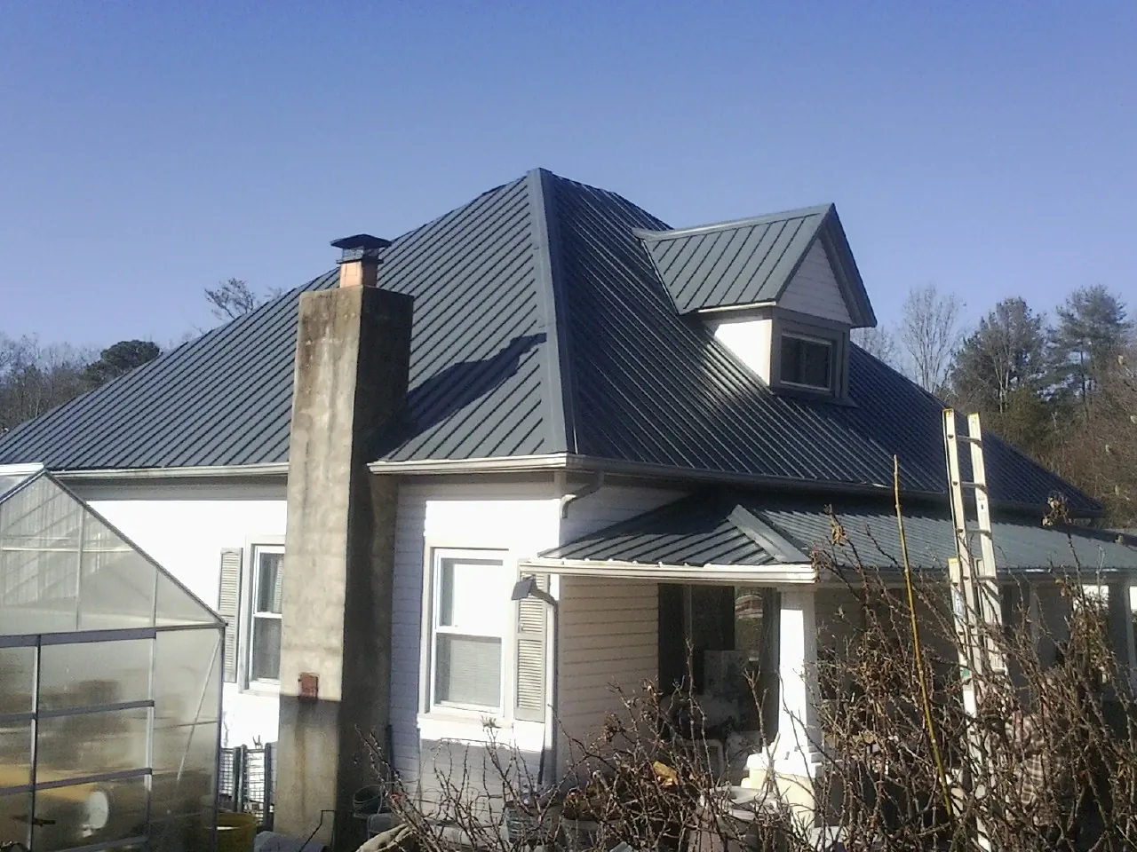 Dark blue standing seam metal roof on a white farmhouse with dormer — Slate & Tile Roof Repair by Roofing Brothers in Tiltonsville