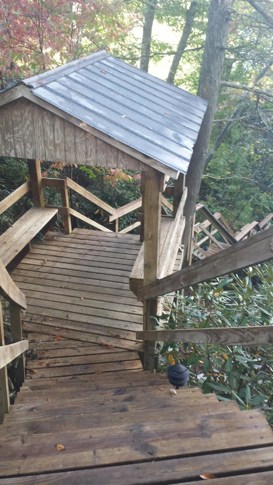 Metal roofed shelter over wooden steps on a wooded walkway — Skylight Repair & Installation work by our crew in Tiltonsville