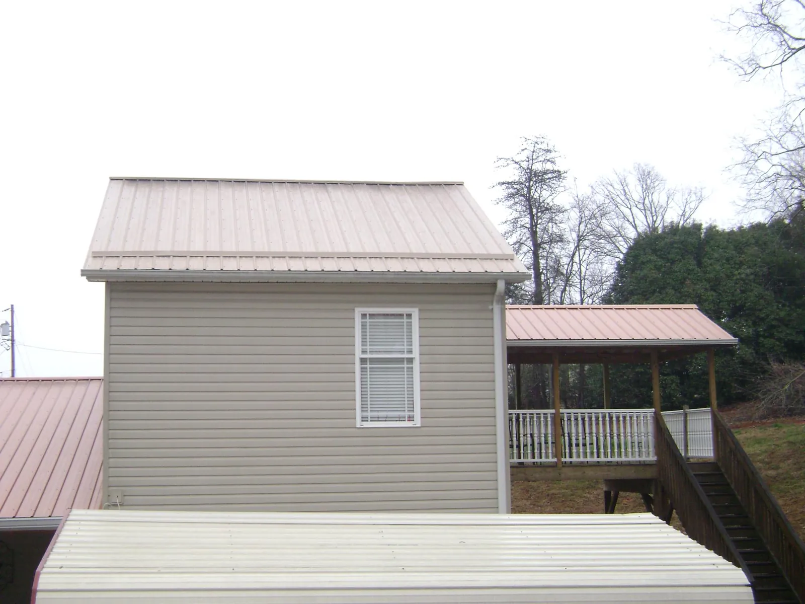 Tan metal roofs on a two story addition and attached porch, from a Roof Replacement job in Tiltonsville