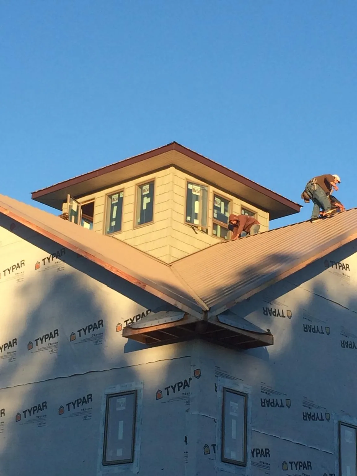 Roofers working around a rooftop cupola on a new metal roof at sunset — Roof Waterproofing in Tiltonsville by Roofing Brothers